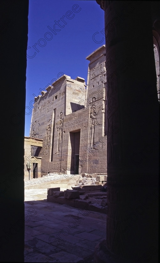 Aswan Philae EG949223jhp 
 Philae Temple courtyard second pylon east colonnade view Ptolemaic Egyptian Isis pylon columns carvings Gods Aswan island was established late in the history of Egypt being mainly Ptolemaic, eventually closing as a religious site around 550AD and being located on an island had remained remarkably untouched. Being relocated onto the Island of Agilkia on the River Nile near Aswan, to save it being flooded after the completion of the High Dam, it is perhaps one of the loveliest and most complete classic Egyptian temples to visit with a peaceful spirituality lacking in many of the land based sites. 
 Keywords: Egypt, Aswan, River Nile, Nubia, Philae Temple, island, pylons, carvings, Ptolemy, Ptolemaic, Isis, cult, relocated, rescued, High Dam, landscape, upright, history, ancient, Egyptian, antiquity, archaeology, Egyptology, Agilkia Island, motorboat, water, beautiful, serene, peaceful, 1994, slide, film, Fuji, RDP, Nikon, FM2, manual, 35mm, scanned, scan